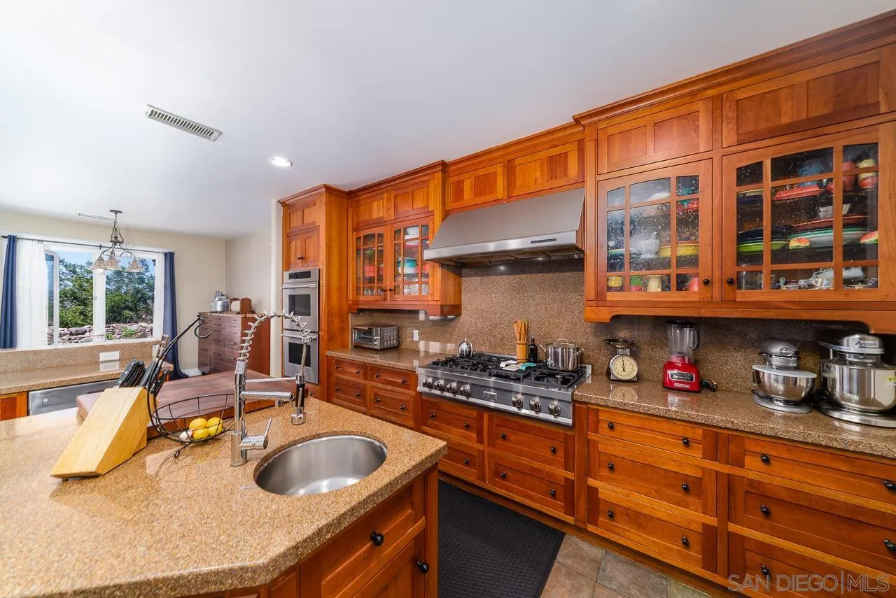 32070 Vía Vera Bonsall, CA 92003 - Photo 10 of 51 a kitchen with granite countertop a stove and cabinets