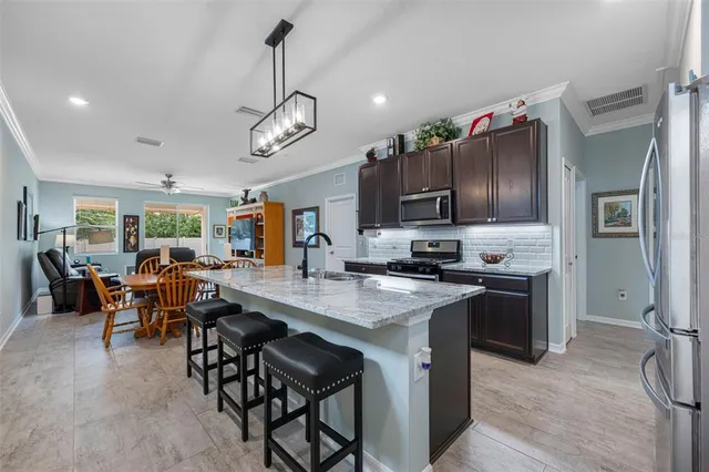 a kitchen with stainless steel appliances granite countertop a dining table chairs stove refrigerator and microwave