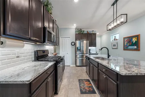 a view of a kitchen counter top space a sink wooden floor and windows