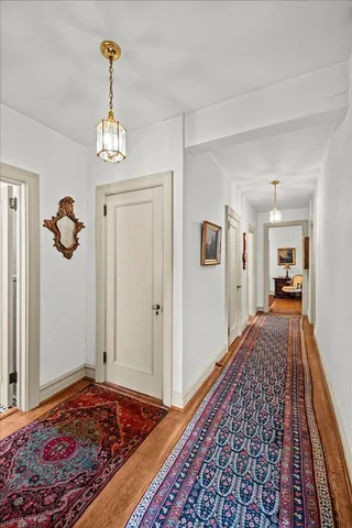 a view of a hallway to a livingroom with wooden floor and a rug