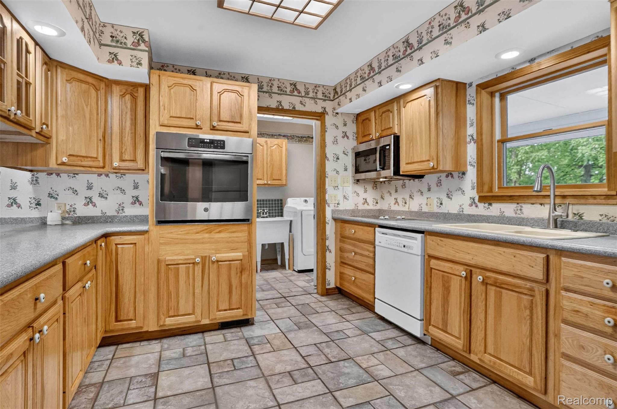 1437 East Cook Road Grand Blanc, MI 48439 - Photo 45 of 69 Kitchen featuring abundant wood cabinetry, gray-flecked countertops, and a tiled floor