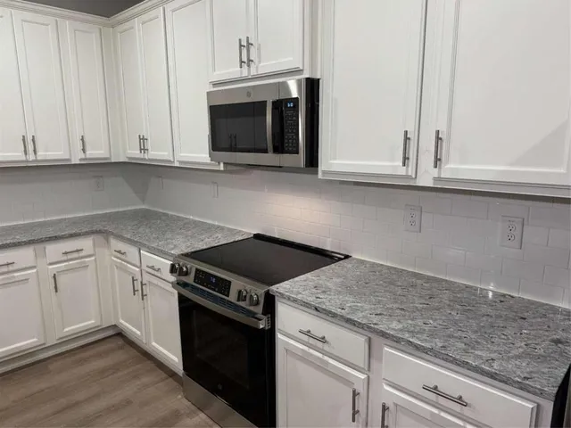 a kitchen with granite countertop white cabinets and a stove