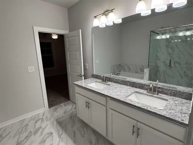 a bathroom with a granite countertop sink a mirror and shower