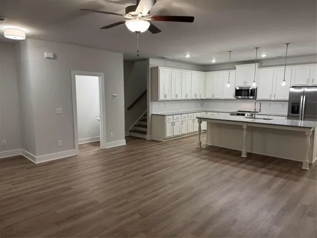 a large kitchen with stainless steel appliances a large counter top a sink a refrigerator and a fireplace