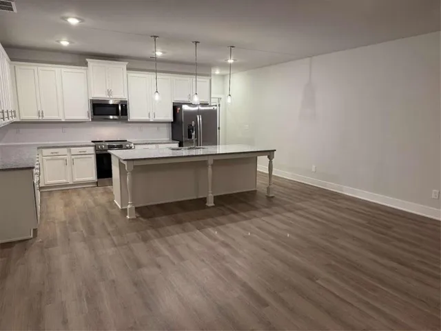 a kitchen with kitchen island granite countertop a sink cabinets and wooden floor