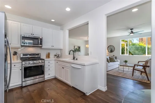 a kitchen with stainless steel appliances white cabinets a sink and a stove