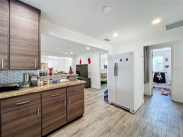 a kitchen with stainless steel appliances granite countertop a refrigerator and wooden floor