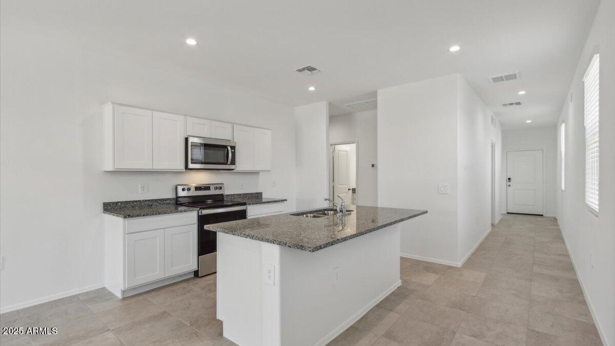 2032 Starkey Avenue Apache Junction, AZ 85120 - Photo 3 of 16 a kitchen with granite countertop white cabinets and stainless steel appliances