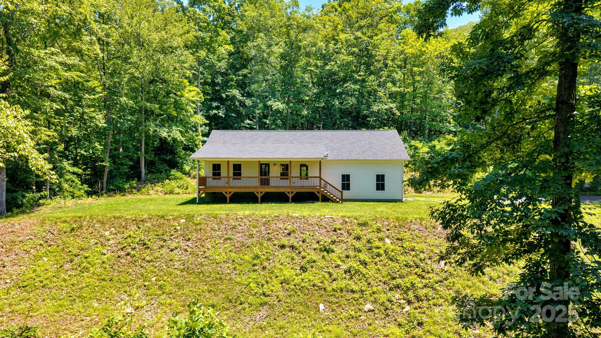 155 Pebble Ridge Road Spruce Pine, NC 28777 - Photo 5 of 39 a yellow house sitting in middle of forest