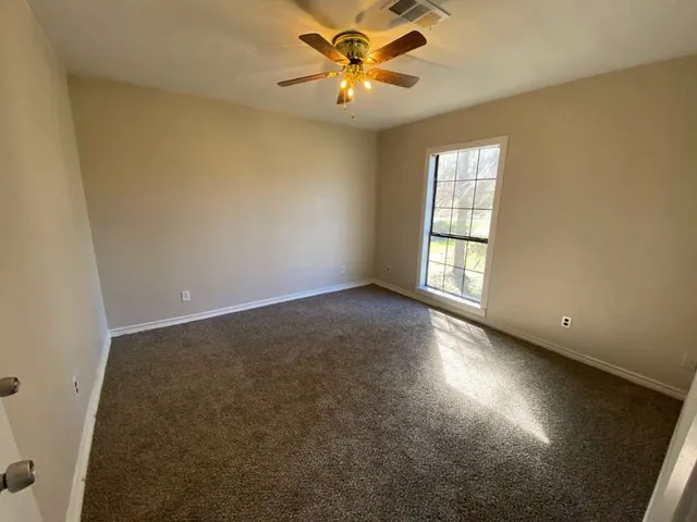 an empty room with windows and fan
