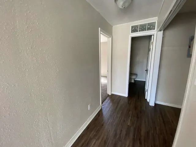 a view of a hallway with wooden floor and closet