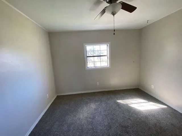 an empty room with a window and a fan
