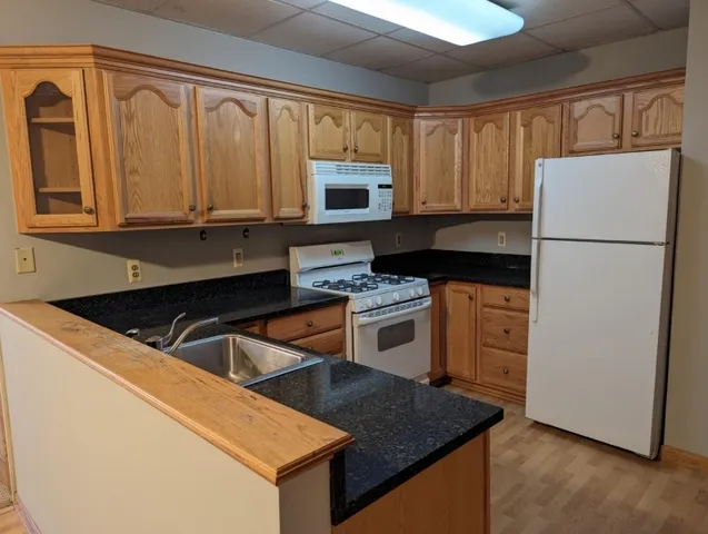 a kitchen with granite countertop a refrigerator stove and sink