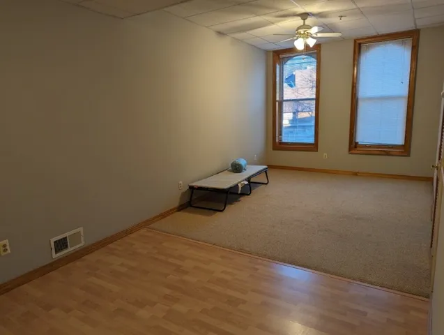 an empty room with windows and chandelier fan