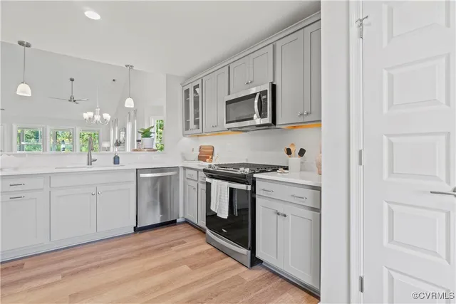 a kitchen with stainless steel appliances granite countertop white cabinets a sink a stove a window and white