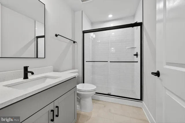 a bathroom with a granite countertop sink mirror vanity and toilet