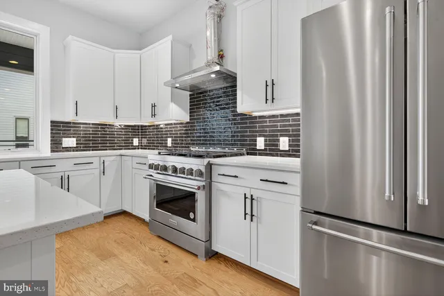 a kitchen with stainless steel appliances white cabinets and a refrigerator