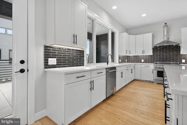 a large white kitchen with granite countertop a white stove top oven and sink