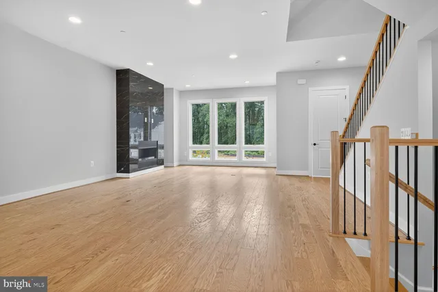 an empty room with wooden floor and fan
