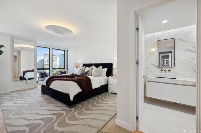 a spacious bedroom with a bed a mirror and lamp