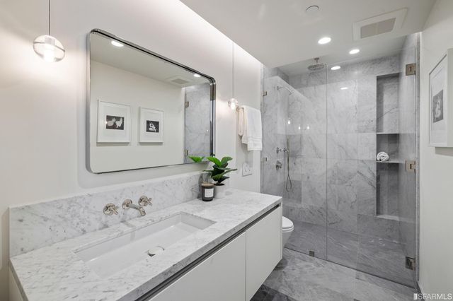 a bathroom with a granite countertop sink a toilet and shower
