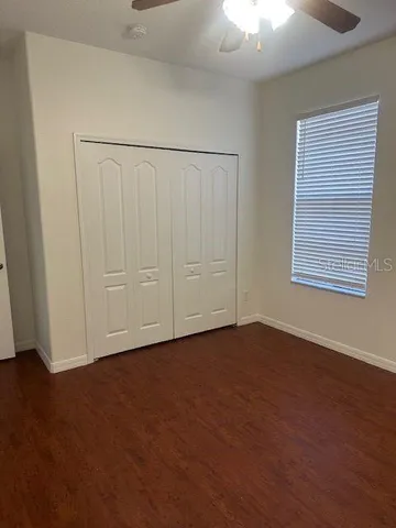 an empty room with wooden floor closet and windows