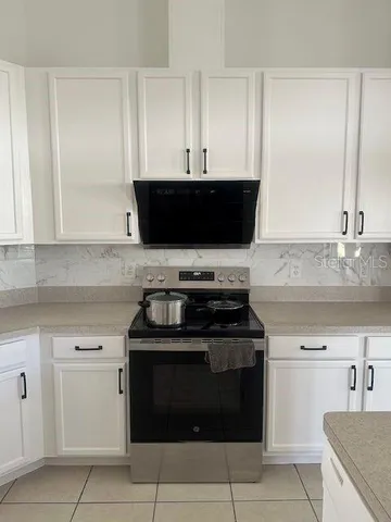 a kitchen with white cabinets and black appliances
