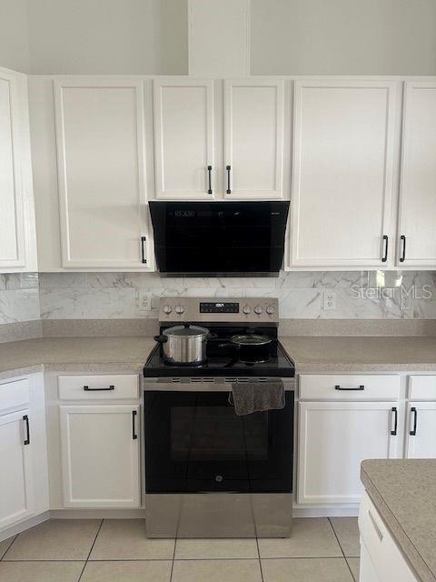 2614 Hartwood Pines Way Clermont, FL 34711 - Photo 6 of 25 a kitchen with white cabinets and black appliances