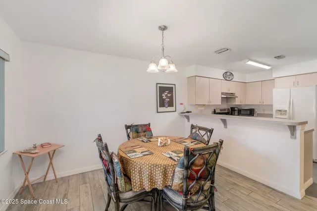 a kitchen with a dining table chairs and refrigerator