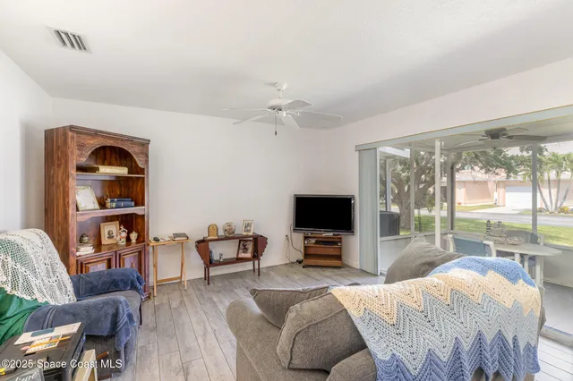 a living room with furniture a flat screen tv and a floor to ceiling window