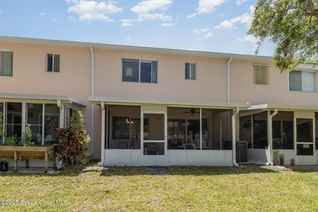 a view of a white house with large windows and a small yard