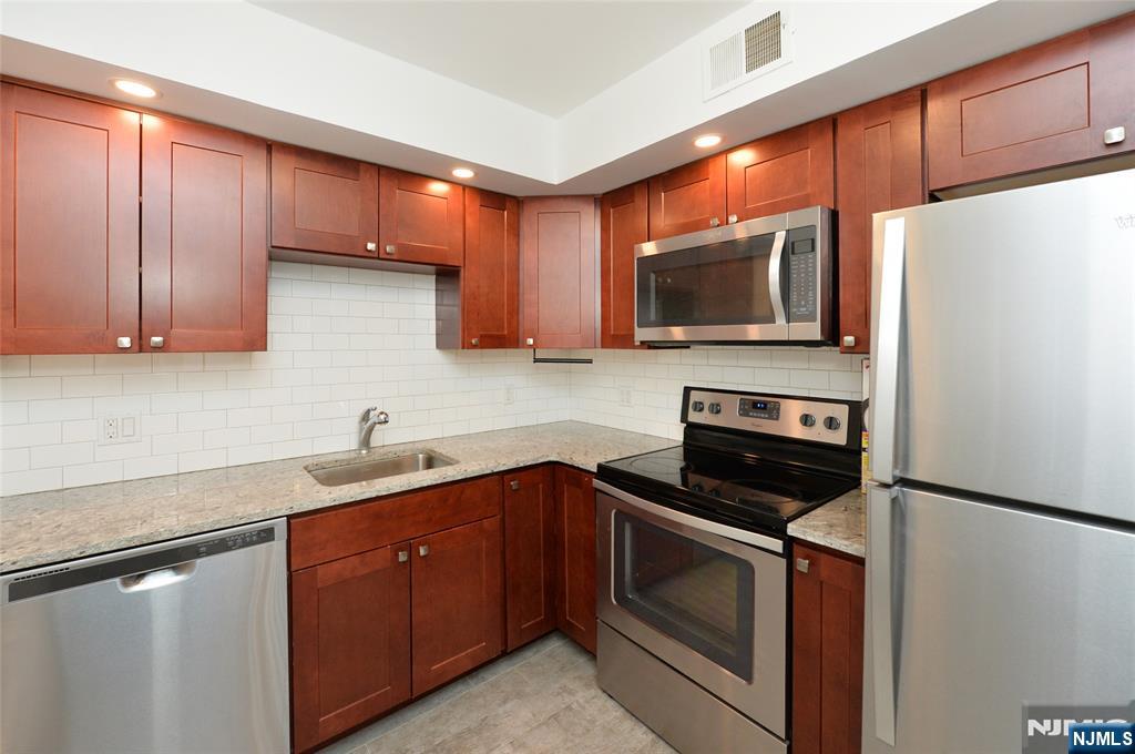 a kitchen with stainless steel appliances granite countertop wooden cabinets stove top oven and sink