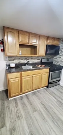 a view of a kitchen with stainless steel appliances granite countertop a stove a sink and a microwave