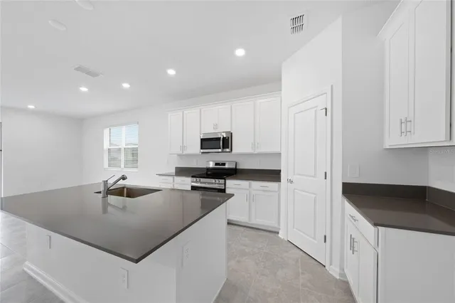 a kitchen with kitchen island a sink a counter top space and appliances