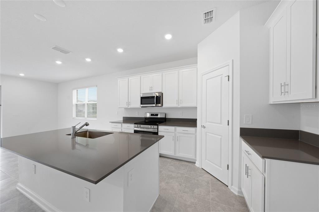 6061 Shavasana Road Clermont, FL 34714 - Photo 8 of 33 a kitchen with kitchen island a sink a counter top space and appliances