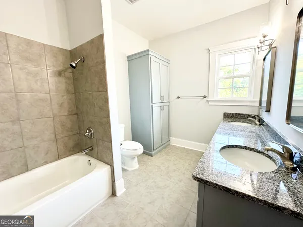 a bathroom with a granite countertop tub sink and mirror