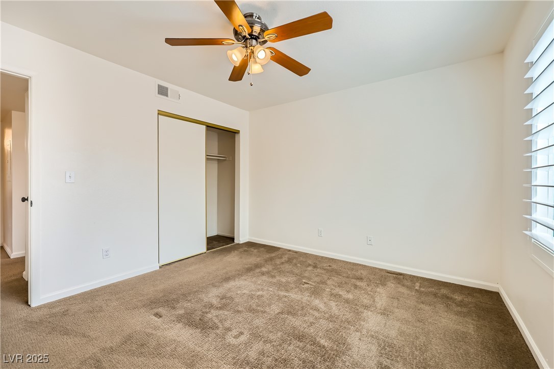 1575 West Warm Springs Road, Unit 1613 Henderson, NV 89014 - Photo 31 of 39 Unfurnished bedroom featuring visible vents, baseboards, a closet, ceiling fan, and carpet flooring