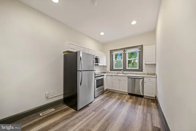 a kitchen with a refrigerator and white cabinets