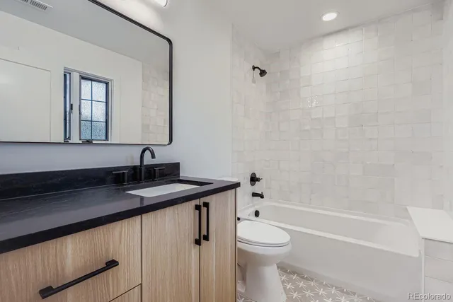 a bathroom with a granite countertop sink a toilet and shower