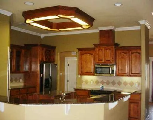 a kitchen with kitchen island granite countertop a refrigerator a stove and a sink with wooden floor