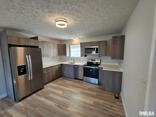a kitchen with granite countertop stainless steel appliances a refrigerator a stove top oven and granite top