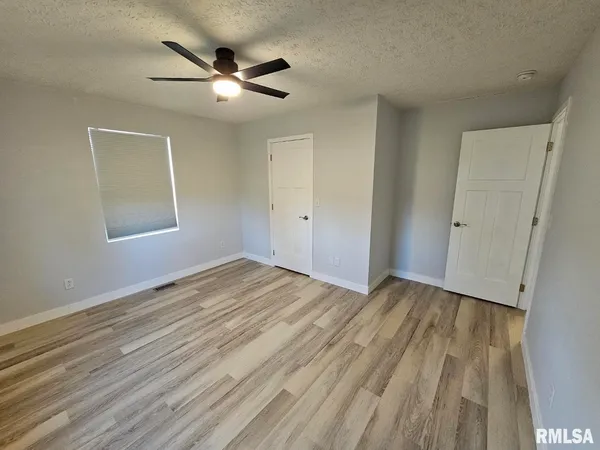 an empty room with wooden floor and ceiling fan