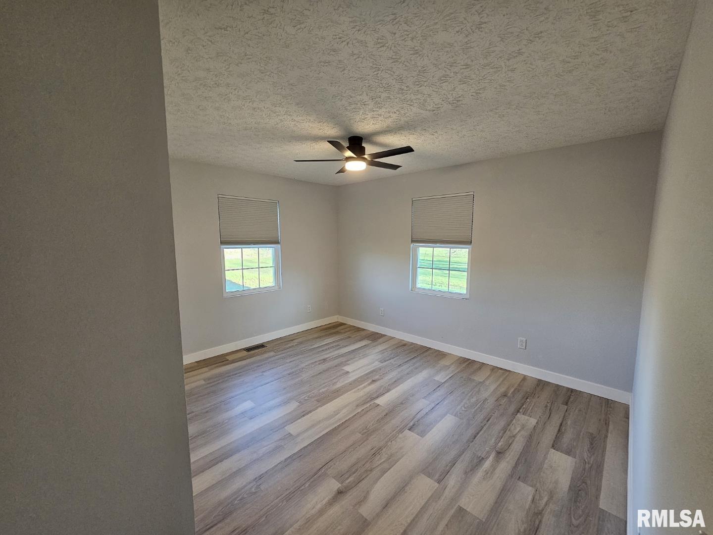 10457 Puckett Lane Mount Vernon, IL 62864 - Photo 21 of 25 an empty room with wooden floor ceiling fan and windows