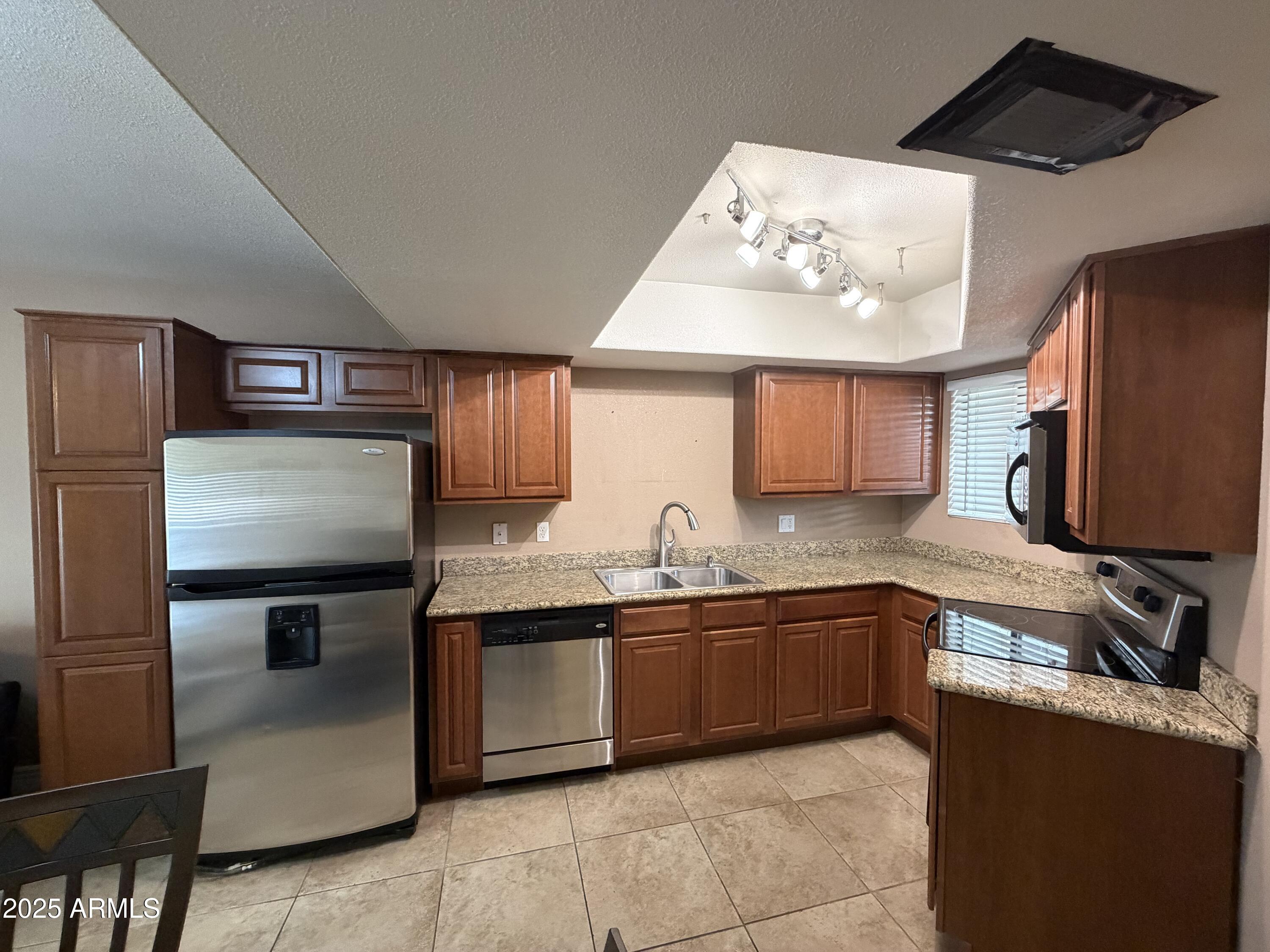 835 North Granite Reef Road, Unit 34 Scottsdale, AZ 85257 - Photo 2 of 13 a kitchen with stainless steel appliances granite countertop a sink and a refrigerator