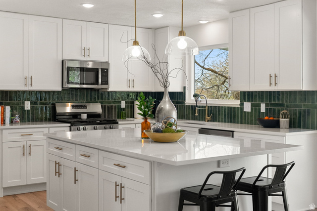 368 Spring Creek Road Providence, UT 84332 - Photo 2 of 45 Kitchen with white cabinetry, stainless steel appliances, a breakfast bar, and light stone countertops