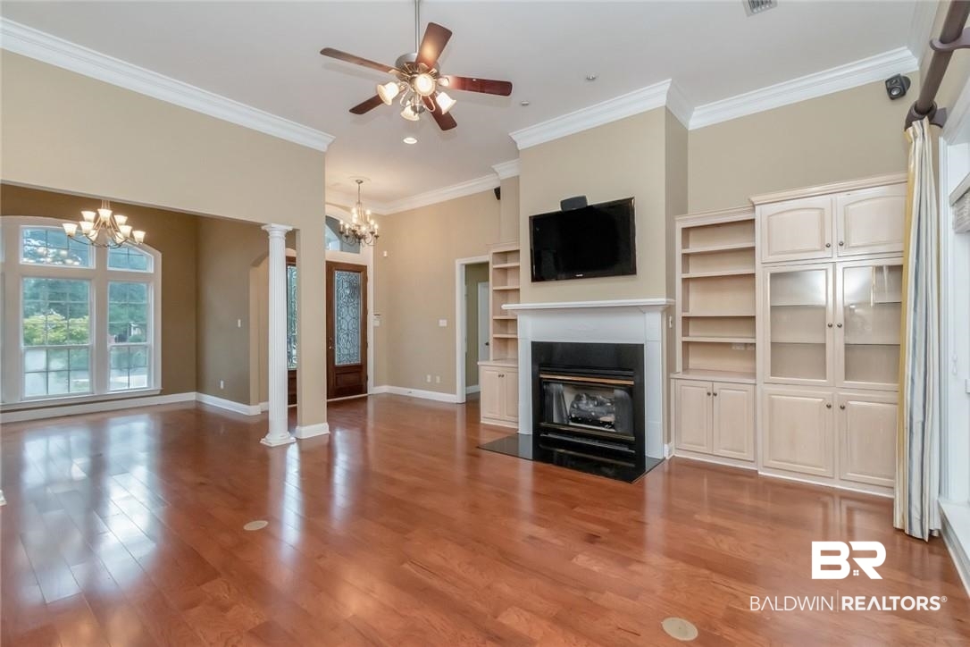 8837 Dawes Lake Road South Mobile, AL 36619 - Photo 8 of 44 Unfurnished living room featuring ornate columns, ceiling fan with notable chandelier, hardwood / wood-style flooring, and ornamental molding