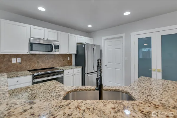 a kitchen with stainless steel appliances granite countertop a refrigerator and a stove top oven