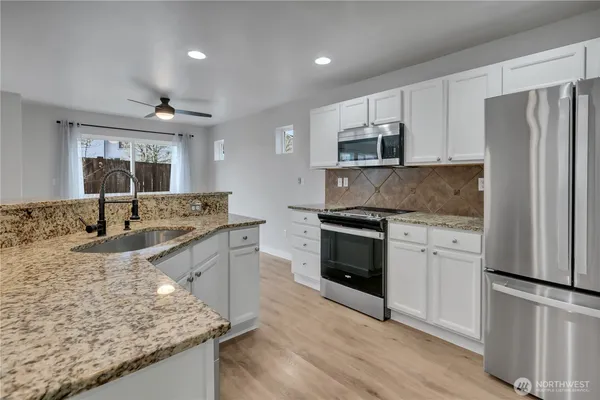a kitchen with stainless steel appliances granite countertop a sink stove and refrigerator