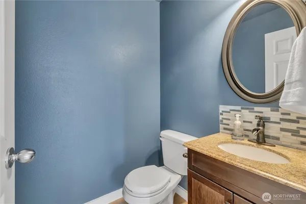 a bathroom with a granite countertop toilet a sink and a mirror