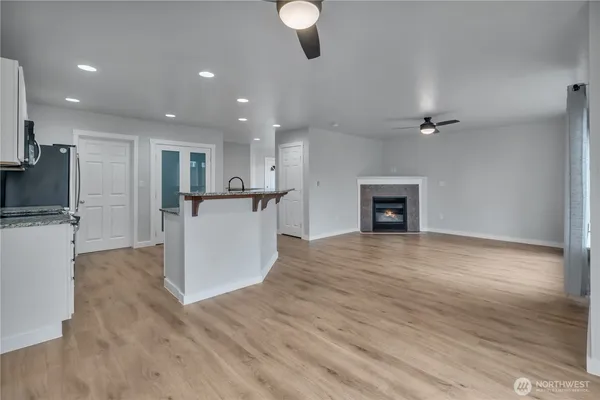 an empty room with wooden floor and a kitchen